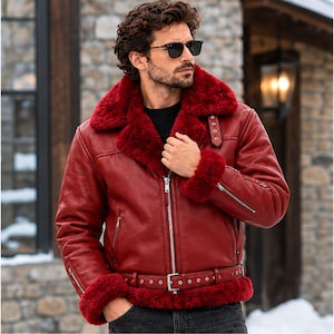 May include: A deep red leather jacket featuring a thick, matching red faux fur lining on the oversized collar and cuffs. The jacket includes a silver front zipper, a buckled waist belt, and zippered pockets on the chest and sleeves for a structured look.