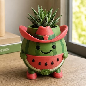 Peut inclure: Un pot de fleurs en forme de pastèque verte avec un visage souriant, portant un chapeau de cowboy rouge et des bottes rouges. Le pot présente un motif de tranche rouge avec des pépins noirs et une boucle de ceinture en forme d'étoile.