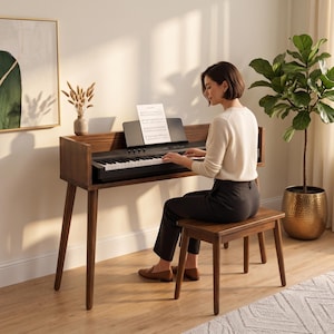 Könnte beinhalten: Ein Digitalpiano aus dunklem Holz mit passender Bank. Das Klavier verfügt über eine schwarze Tastatur, einen Notenständer mit Notenblatt und vier konisch zulaufende Beine. Die Konsole hat ein klares, rechteckiges Design mit glatter Oberfläche.