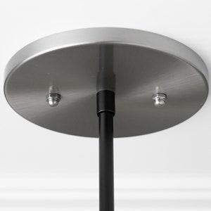 May include: A brushed nickel ceiling plate with two mounting screws and a black hanging rod.