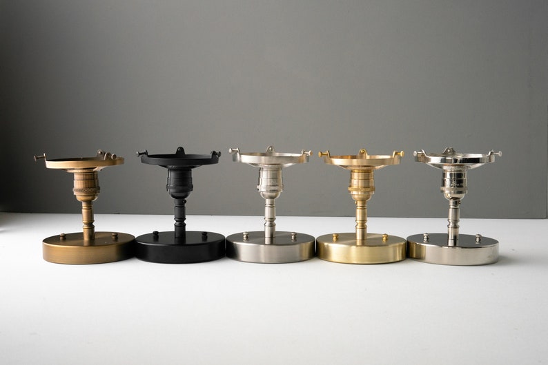 May include: Five ceiling light fixture base plates in different finishes: brass, black, nickel, gold, and silver.