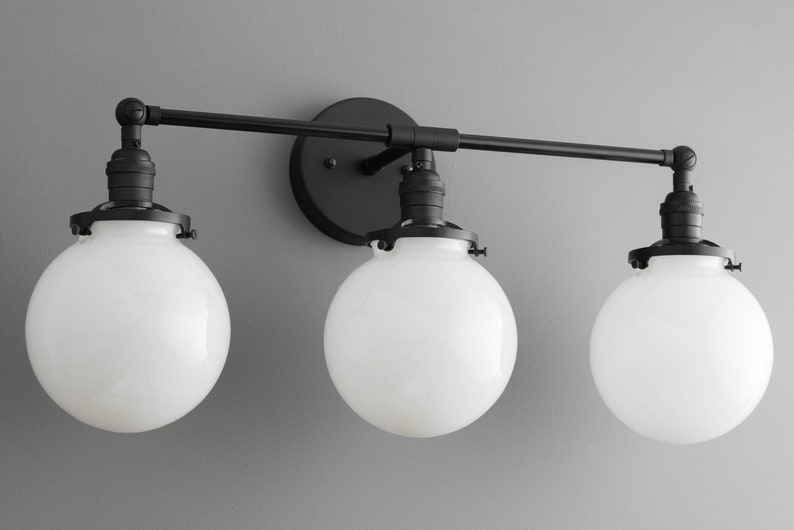May include: Black three-light bathroom vanity fixture with globe-shaped frosted glass shades.