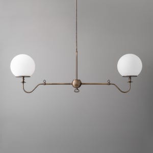 May include: A bronze-toned, two-light pendant light fixture with two spherical, white glass shades. The fixture has a central stem and horizontal arms with decorative details, ideal for kitchen or dining room lighting.