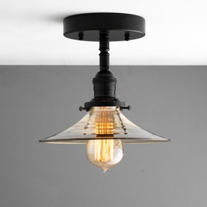May include: A black ceiling light fixture with a clear glass shade and a vintage-style light bulb.