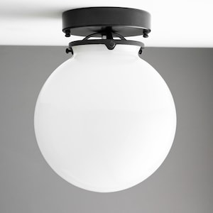 May include: A black ceiling light fixture with a white globe-shaped glass shade.