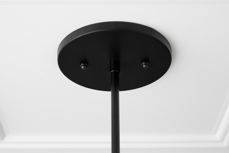 May include: Black ceiling mount for a pendant light fixture. The mount has two screws and a round, flat base.