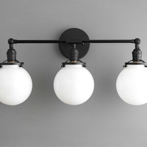 May include: Black three-light vanity light fixture with white globe shades.