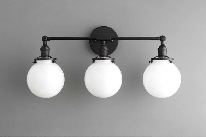 May include: Black three-light vanity light fixture with white globe shades.