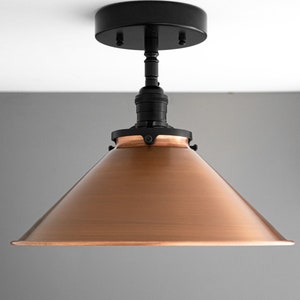 May include: A copper-colored cone-shaped lampshade with a black metal base and a black ceiling mount.
