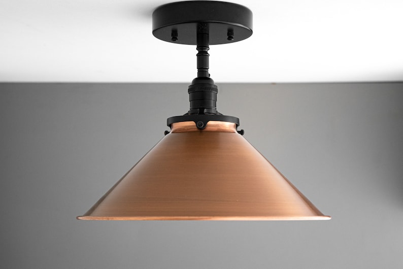 May include: A copper-colored cone-shaped lampshade with a black metal base and a black ceiling mount.
