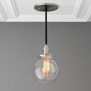 May include: A silver pendant light with a clear glass globe shade and a black cord.