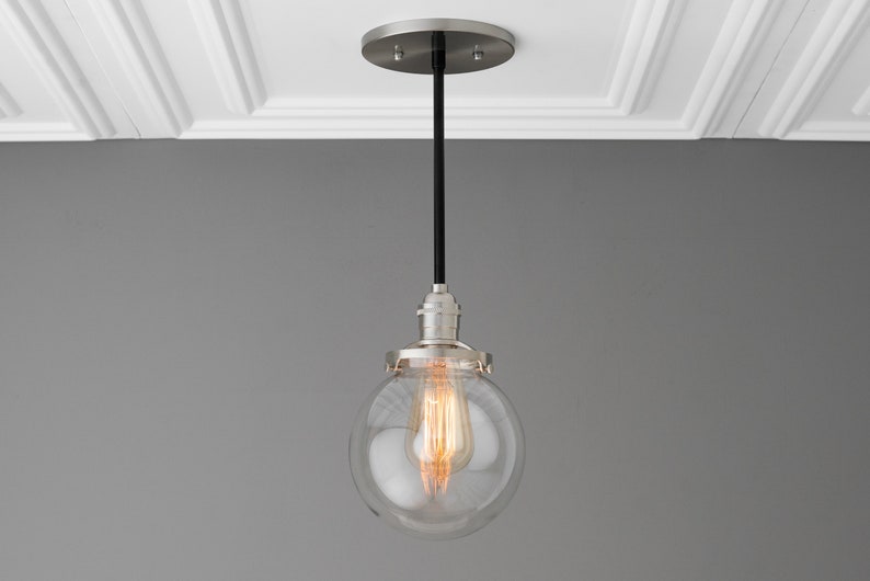 May include: A silver pendant light with a clear glass globe shade and a black cord.