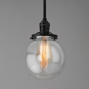 May include: A black pendant light with a clear glass globe shade and a vintage-style filament light bulb.