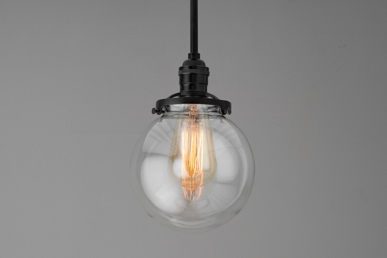 May include: A black pendant light with a clear glass globe shade and a vintage-style filament light bulb.