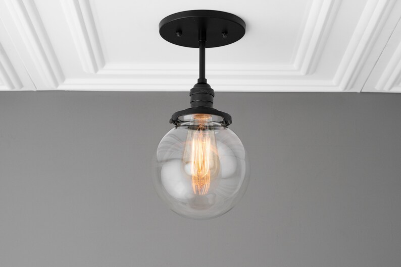 May include: A black ceiling light fixture with a clear glass globe shade and a single light bulb.