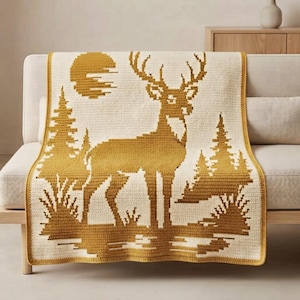 May include: A rectangular crochet blanket featuring a two-tone mustard yellow and cream design. The pattern displays a central standing deer, pine trees on both sides, and a circular sun shape in the upper left corner, all in a grid-like texture.