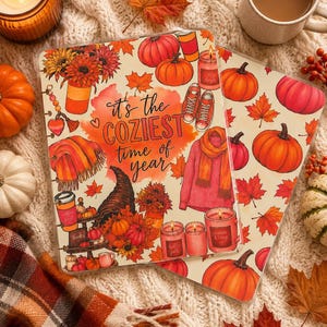 Könnte beinhalten: Zwei rechteckige, durchsichtige Kunststoffhüllen mit einer herbstlichen Illustration aus Kürbissen, Ahornblättern, einem Pullover, Kerzen, einem Kaffeebecher und Turnschuhen. Der Text lautet "it's the COZIEST time of year" in schwarzer Schrift.
