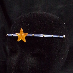 May include: A blue headband with gold accents and a large orange star in the center.