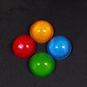 May include: Four round, shiny, decorative ornaments with glitter. The ornaments are red, blue, green, and orange.
