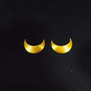 May include: A pair of gold crescent moon shaped earrings.