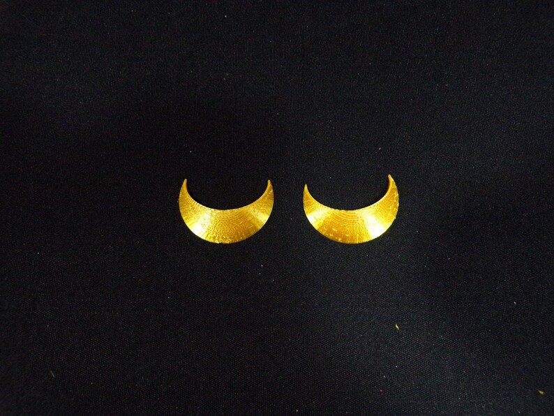 May include: A pair of gold crescent moon shaped earrings.