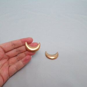 May include: Two gold crescent moon shaped earrings.