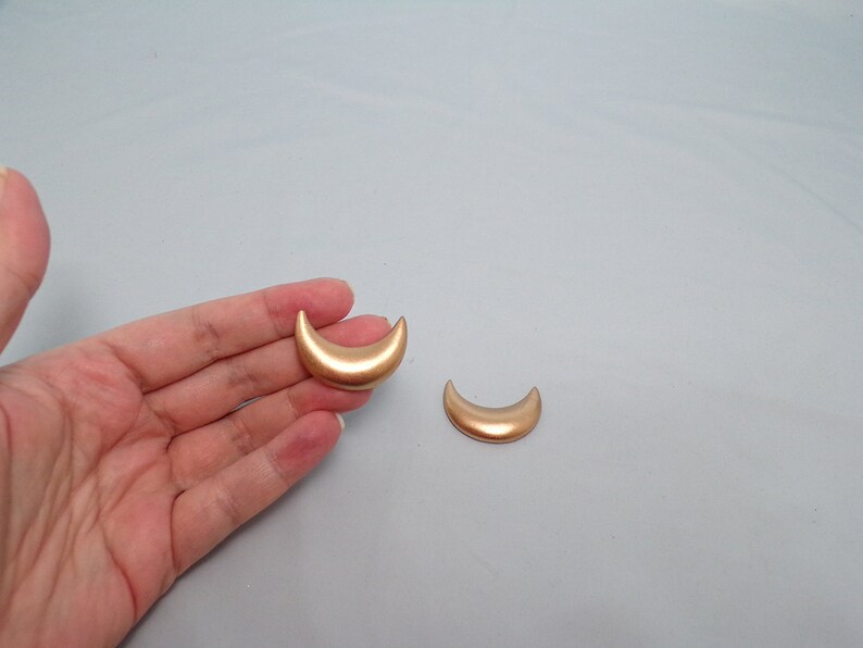 May include: Two gold crescent moon shaped earrings.