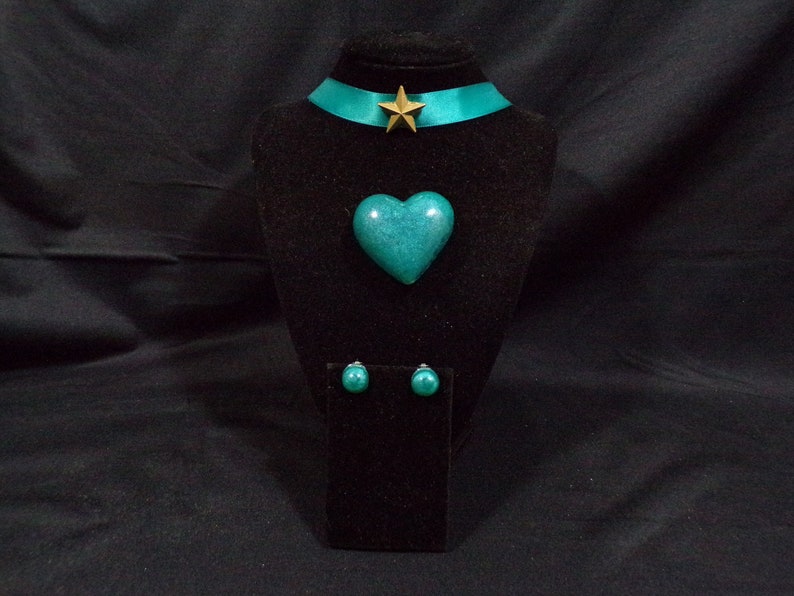 May include: Teal heart-shaped pendant necklace with matching earrings and a gold star charm on a teal ribbon choker.