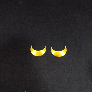 May include: Two gold crescent moon shaped earrings.