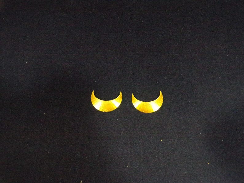 May include: Two gold crescent moon shaped earrings.