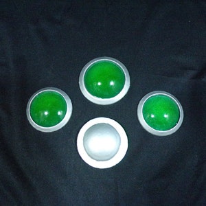 May include: Four round, silver-rimmed buttons with green centers. One button is white.
