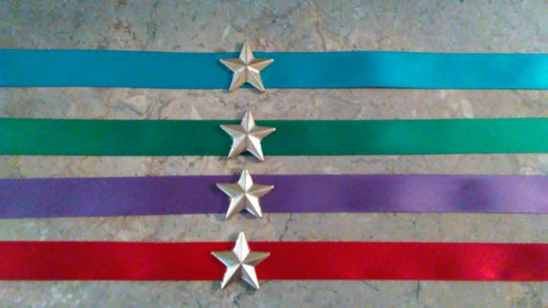 May include: Four satin ribbon strips with silver star embellishments. The ribbons are turquoise, green, purple, and red.