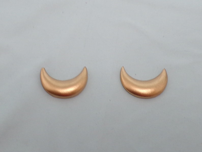 May include: A pair of gold crescent moon earrings. The earrings are made of a smooth, shiny metal.