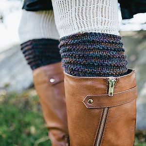 May include: A pair of brown leather boots with a zipper on the side. The boots are worn with white and multi-colored knitted leg warmers.