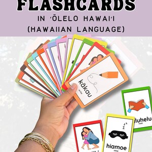 May include: A set of educational flashcards featuring action verbs in the Hawaiian language, 'Ōlelo Hawai'i. The cards display colourful borders, illustrations, and text labels in both Hawaiian and English, such as kākau, pūliki, and hiamoe.