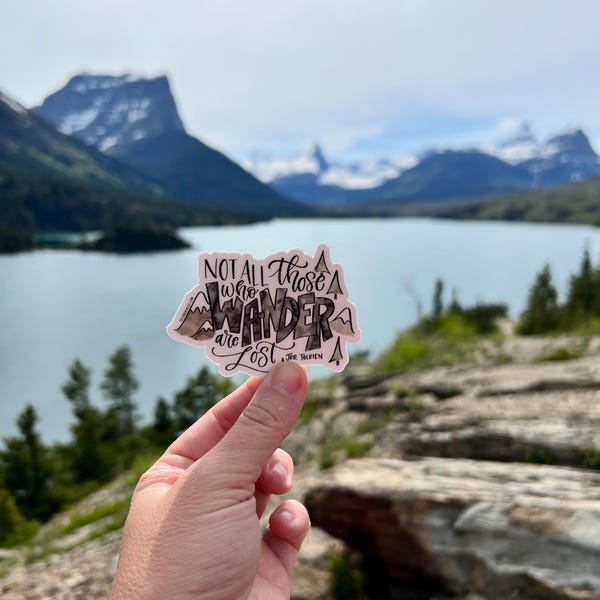 May include: A sticker featuring a mountain range design and the text "Not all those who wander are lost - J.R.R. Tolkien" in black lettering.