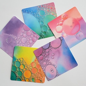 May include: Five square cards with colorful abstract designs featuring a pattern of overlapping circles. The circles are filled with a variety of colors, including pink, blue, green, yellow, and orange.