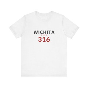 May include: A white short-sleeve t-shirt featuring the text WICHITA in black capital letters, followed by three red asterisks, and the number 316 in large red font centered on the chest. The garment has a crew neckline and a standard fit.