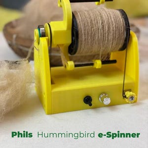 Op de afbeelding: Een felgele Phils Hummingbird e-Spinner met een zwarte spoel omwikkeld met beige vezels. Het apparaat is voorzien van een zwarte tuimelschakelaar, een zilveren bedieningsknop en een kleine gele spanningsregelaar op de voorste basis.