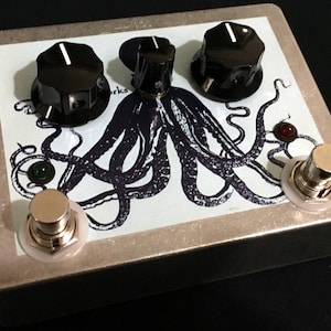 May include: A silver effects pedal with a black and white octopus graphic and three knobs. The pedal has two footswitches and the text "Octopus Works" is visible.