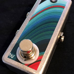 May include: A silver effect pedal with a blue, green, and red swirl design. The pedal has a single footswitch with a white ring around it and the text "bw" on the side.