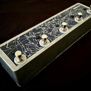 May include: A silver metal foot pedal with five buttons. The buttons are silver with white plastic surrounds. The top of the pedal has a black background with a white star chart design. The text "remarkable" is printed on the pedal.