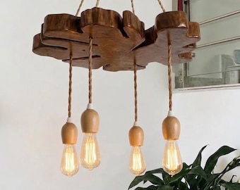 Puede incluir: Una lámpara de araña con una base grande de madera natural de color marrón oscuro con formas irregulares, suspendida por cuerdas. Cuatro luminarias cuelgan de la madera, cada una con un casquillo de madera clara y una bombilla Edison.