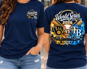 May include: A navy blue t-shirt featuring a small World Series 2026 logo on the front chest. The back displays a large graphic with the text World Series 2026, a baseball, two bats, a stadium silhouette, and team logos for the Brewers and Rays.
