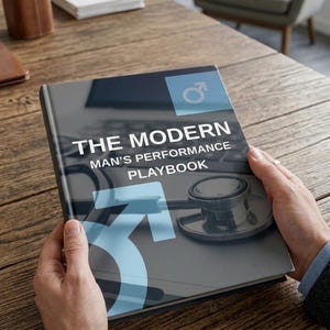 May include: A hardcover book titled The Modern Man's Performance Playbook with a dark gray cover featuring a light blue male gender symbol and a black medical stethoscope graphic. The title is printed in white capital letters on the front cover.