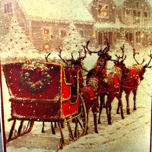 May include: Rectangular Christmas-themed wall art featuring a snowy scene with a red sleigh pulled by reindeer. The sleigh is decorated with a wreath, and houses are in the background. The art has a wire hanger.