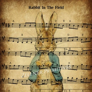 Può includere: Una stampa in stile vintage con uno spartito musicale e un'illustrazione ad acquerello di un coniglio con una giacca blu. Il testo "Rabbit In The Field" è in alto, con "Zellner Primitives" al centro.