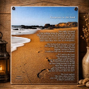 Peut inclure: Panneau carré en bois avec une scène de plage : sable, mer et ciel. Le panneau porte l'inscription « Footprints in the Sand » et un poème sur la foi. Suspendu par un fil noir, il présente une esthétique rustique et vintage.