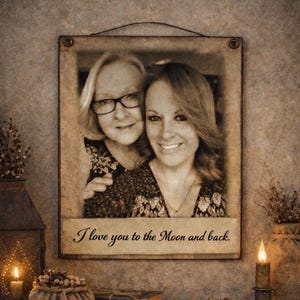 May include: A sepia-toned framed photograph featuring two smiling women. The frame is rectangular with a dark metal wire for hanging. The text "I love you to the Moon and back" is printed on the bottom of the frame.