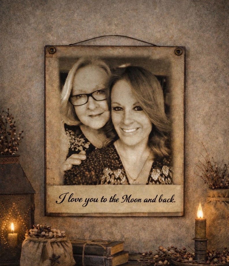 May include: A sepia-toned framed photograph featuring two smiling women. The frame is rectangular with a dark metal wire for hanging. The text "I love you to the Moon and back" is printed on the bottom of the frame.